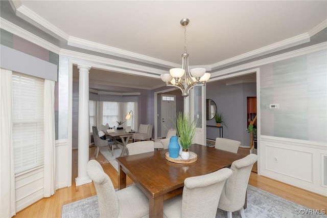 dining room featuring a chandelier, ornate columns, crown molding, and light wood-style floors