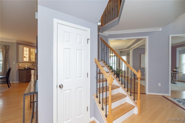 stairway with crown molding, baseboards, and wood finished floors