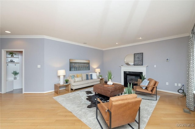 living room featuring ornamental molding, recessed lighting, light wood-style floors, a fireplace, and baseboards