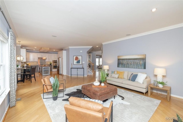 living room with recessed lighting, baseboards, crown molding, and light wood finished floors