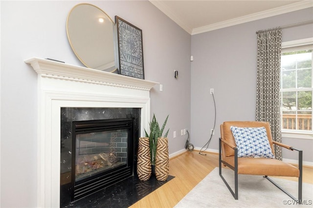 sitting room with a high end fireplace, baseboards, wood finished floors, and crown molding