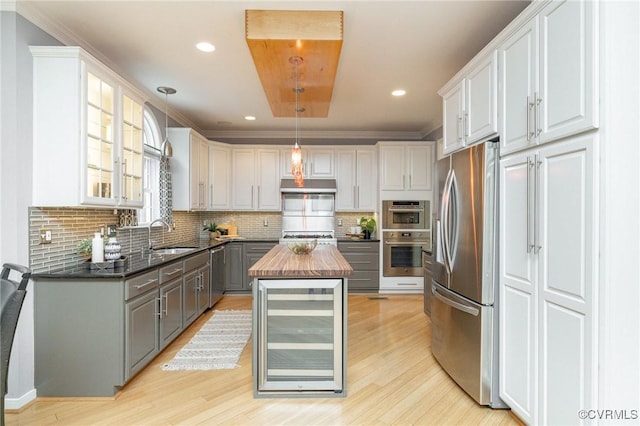 kitchen featuring beverage cooler, gray cabinets, appliances with stainless steel finishes, wood counters, and a center island