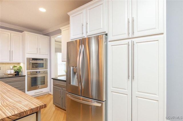 kitchen featuring stainless steel appliances, dark countertops, white cabinets, and crown molding