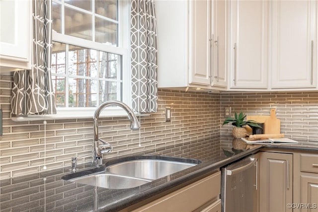 kitchen with tasteful backsplash, dishwasher, dark stone counters, white cabinets, and a sink