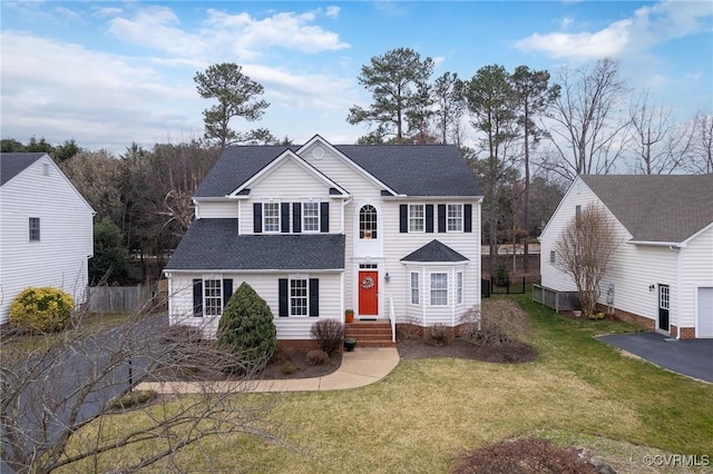 view of front of home featuring aphalt driveway, roof with shingles, a front lawn, and fence