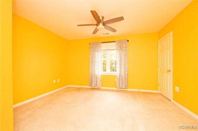 spare room featuring light carpet, baseboards, and a ceiling fan