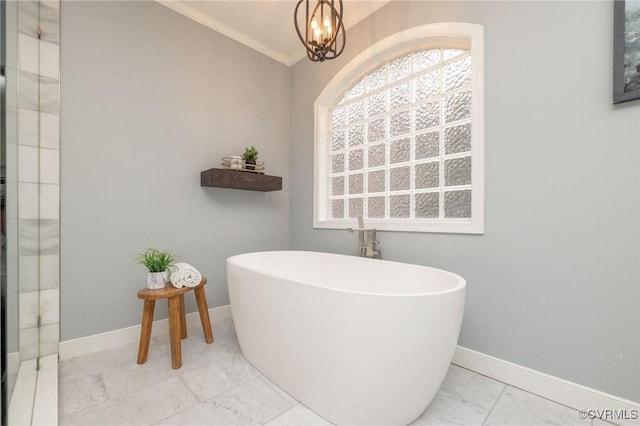 full bathroom featuring crown molding, baseboards, a chandelier, a soaking tub, and marble finish floor