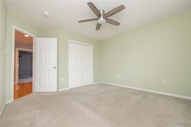 unfurnished bedroom with ceiling fan, carpet, a closet, and baseboards