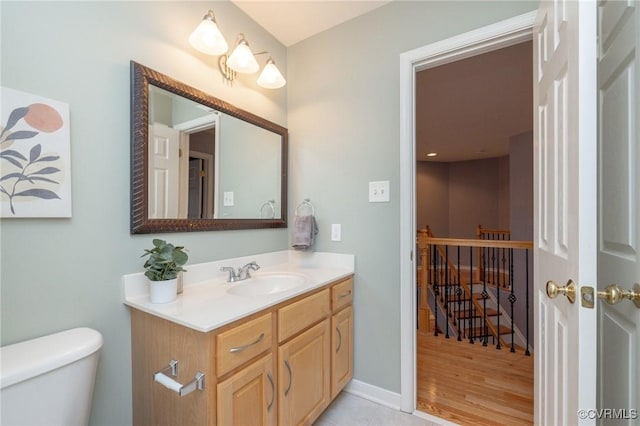 half bath with tile patterned floors, baseboards, toilet, and vanity