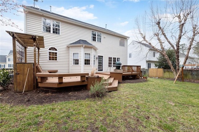 rear view of house featuring a yard, a deck, and fence