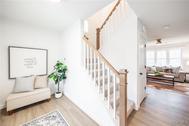 stairs with a ceiling fan, wood finished floors, and baseboards