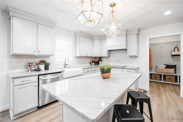 kitchen with a notable chandelier, a sink, a kitchen breakfast bar, white cabinetry, and dishwasher