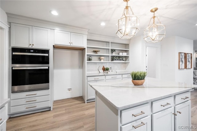 kitchen featuring light stone counters, open shelves, light wood-style flooring, double oven, and a chandelier