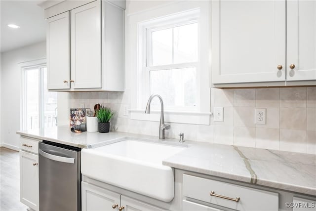 kitchen featuring light stone counters, recessed lighting, a sink, decorative backsplash, and stainless steel dishwasher