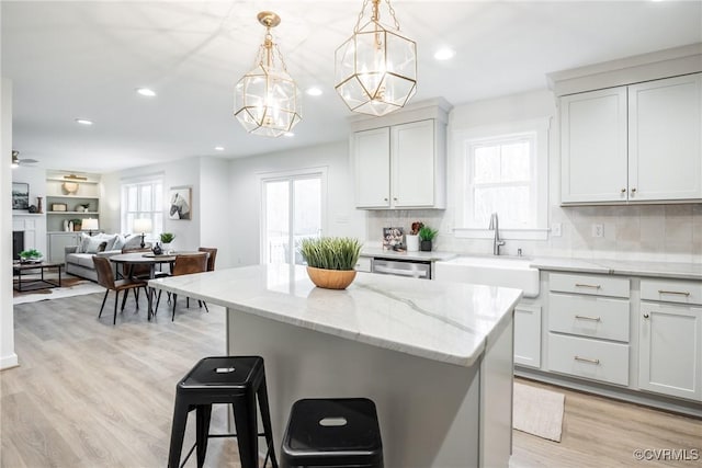 kitchen featuring light wood-style flooring, a kitchen island, a wealth of natural light, and a sink