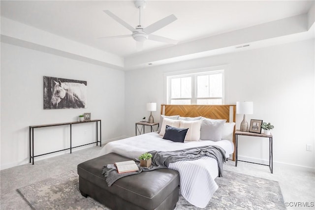 bedroom featuring visible vents, ceiling fan, baseboards, a tray ceiling, and carpet floors