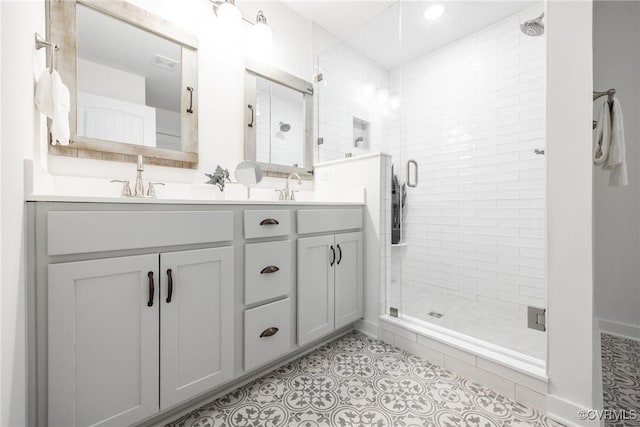 full bathroom with double vanity, visible vents, a stall shower, and a sink