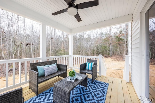 wooden deck with a ceiling fan, a forest view, and an outdoor hangout area