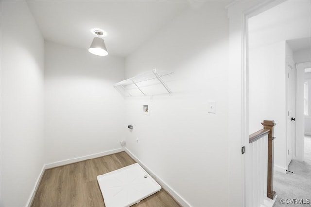 clothes washing area with baseboards, hookup for a washing machine, laundry area, and light wood finished floors