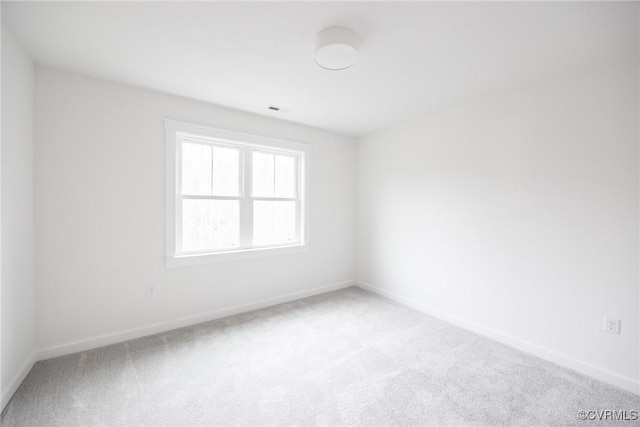 empty room with visible vents, light colored carpet, and baseboards