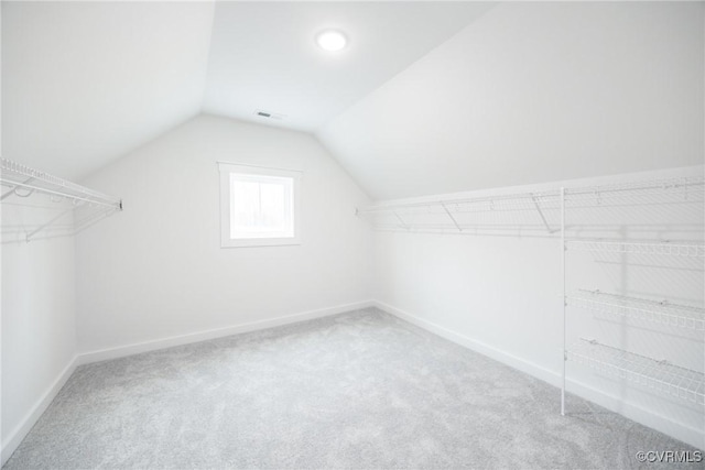 walk in closet with visible vents, carpet, and vaulted ceiling