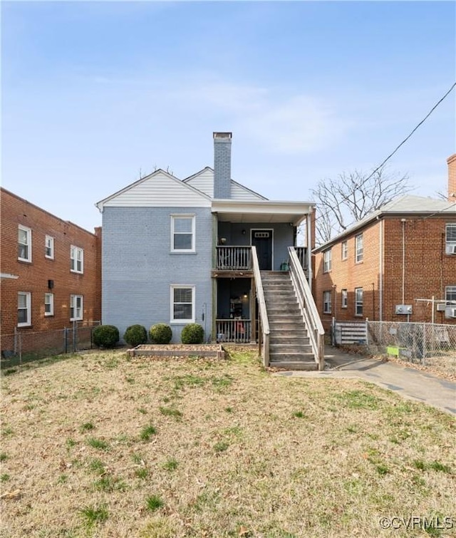 back of house with stairway, a chimney, and fence