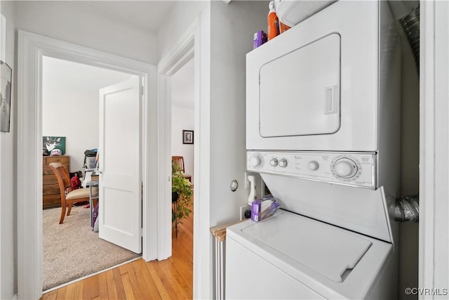 washroom featuring stacked washer / drying machine, light wood-style floors, and laundry area