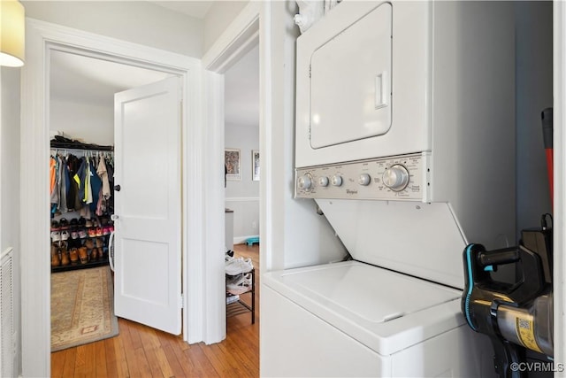 laundry room featuring laundry area, stacked washer and clothes dryer, and light wood-type flooring