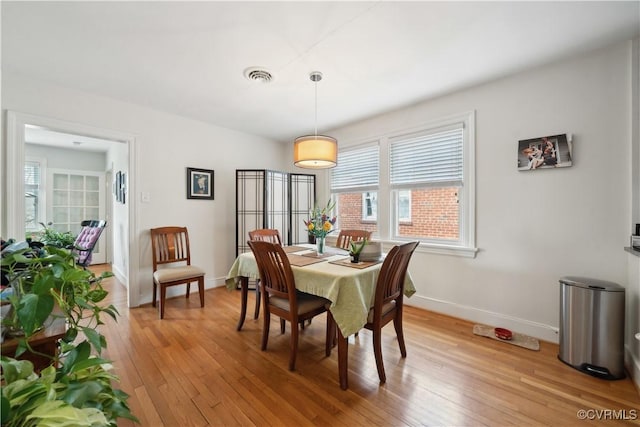 dining area featuring light wood finished floors, visible vents, and baseboards