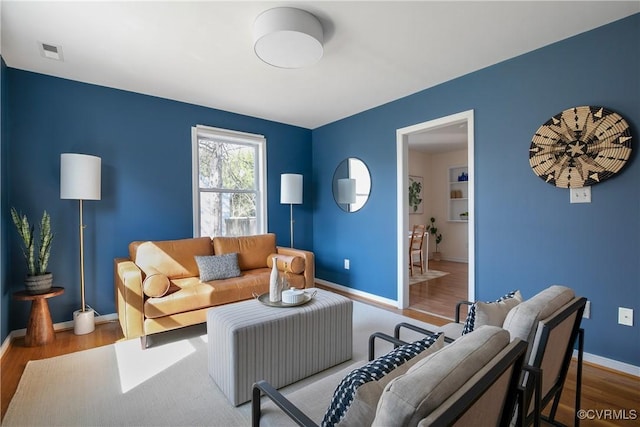 living area with visible vents, wood finished floors, and baseboards