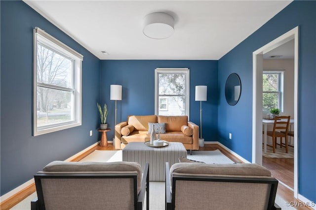 living area with visible vents, wood finished floors, baseboards, and a wealth of natural light