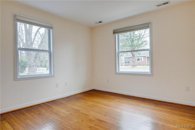 unfurnished room with light wood-style flooring, baseboards, and visible vents