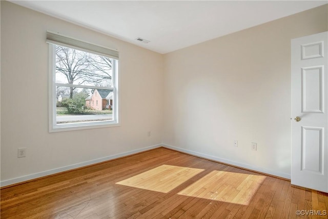 spare room featuring hardwood / wood-style flooring, visible vents, and baseboards