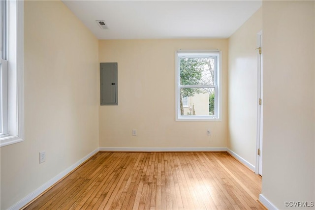 unfurnished room featuring electric panel, visible vents, baseboards, and light wood-style floors