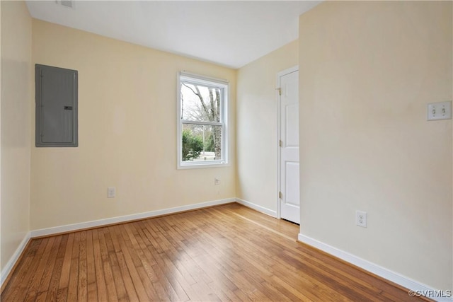 empty room featuring electric panel, baseboards, and hardwood / wood-style flooring