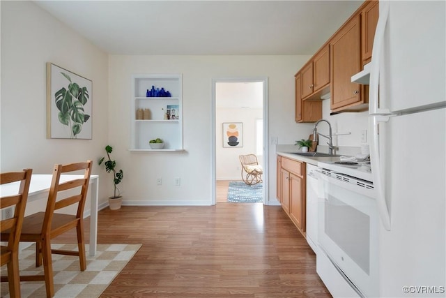 kitchen featuring light countertops, light wood-type flooring, brown cabinetry, white appliances, and a sink