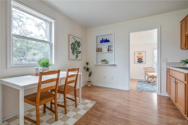 dining area featuring baseboards, built in shelves, and light wood-style flooring