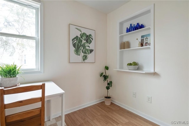 interior space featuring built in shelves, baseboards, and wood finished floors