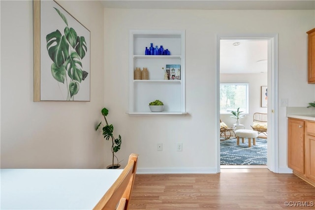 interior space with built in features, baseboards, and light wood-style floors