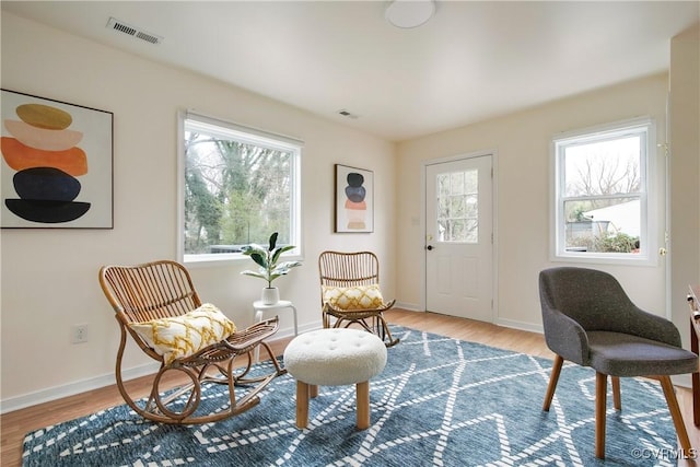 sitting room with visible vents, baseboards, and wood finished floors