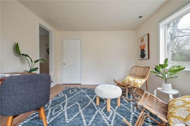 sitting room with wood finished floors, visible vents, and baseboards