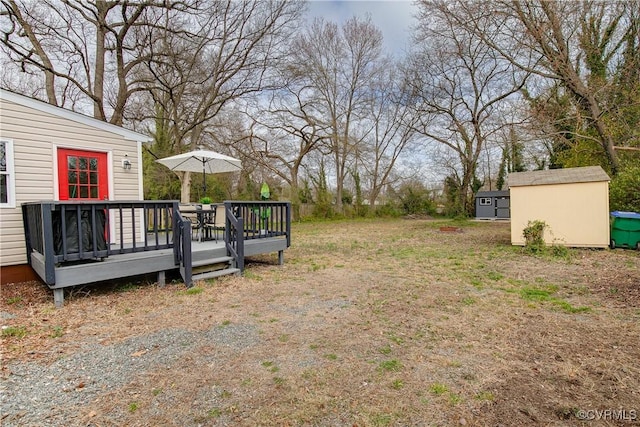 view of yard featuring a wooden deck, an outbuilding, and a shed