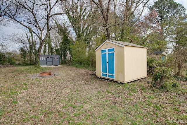 view of yard featuring a storage shed, an outdoor structure, and an outdoor fire pit