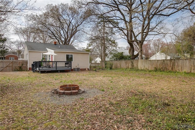 view of yard with a wooden deck, a fenced backyard, and a fire pit