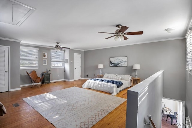 bedroom with attic access, crown molding, and wood finished floors