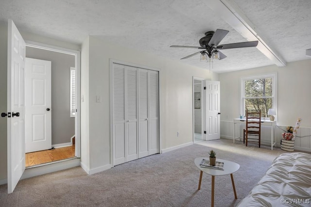 carpeted living room with ceiling fan, baseboards, and a textured ceiling