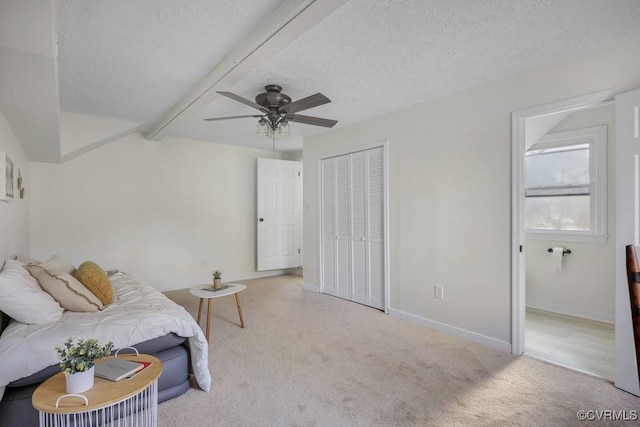 bedroom featuring baseboards, beamed ceiling, carpet flooring, a closet, and a textured ceiling