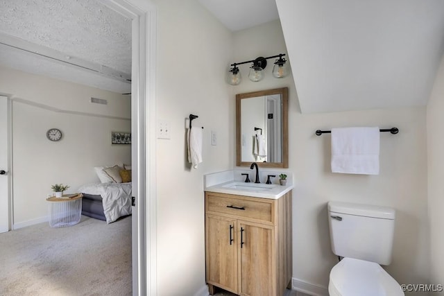 ensuite bathroom featuring visible vents, connected bathroom, baseboards, toilet, and vanity