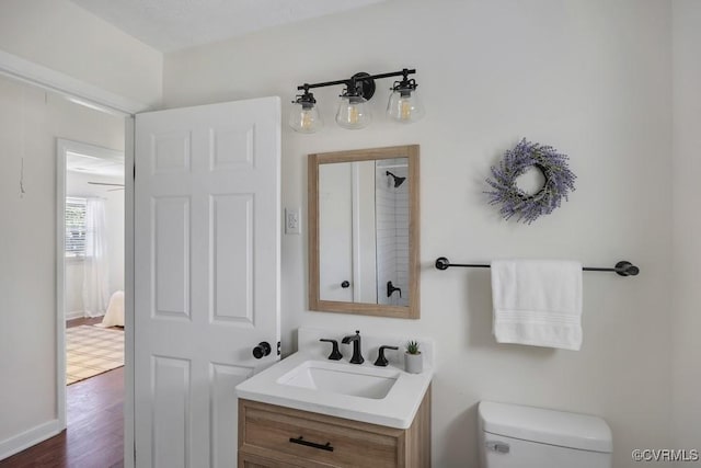 bathroom featuring vanity, toilet, wood finished floors, and baseboards