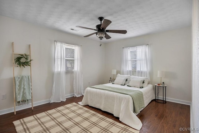 bedroom with visible vents, a ceiling fan, a textured ceiling, wood finished floors, and baseboards